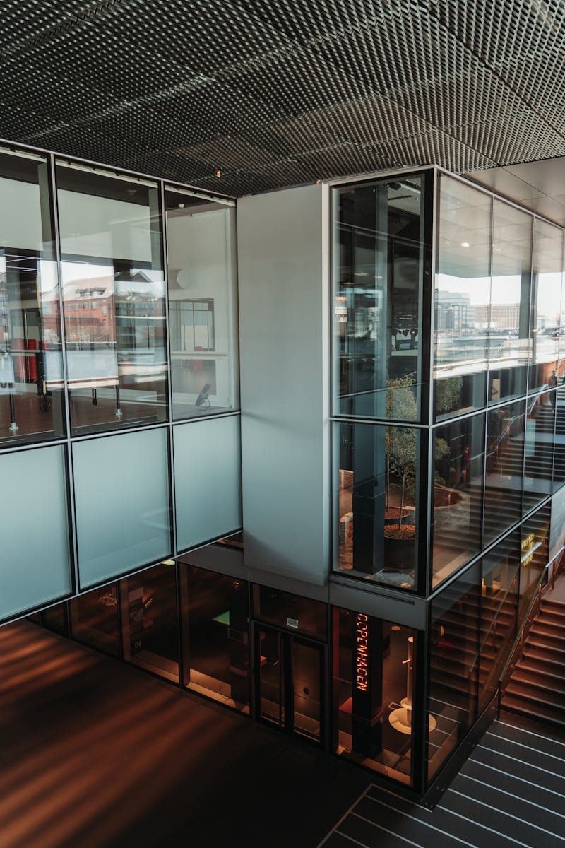 Spacious modern office interior with glass walls and natural lighting.
